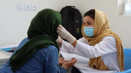 Woman examines patient in mobile health clinic, Afghanistan