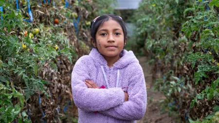 Girl wearing purple sweater with arms acrossed standing in plantation