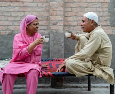 Woman and man facing each other holding tea cups while sitting on benches