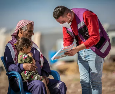 Man weating purple vest showing information to man sitting on chair with a little girl sitting on his lap