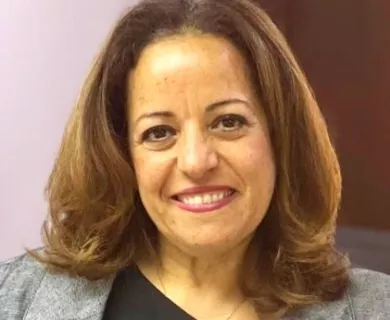 Portrait of woman with shoulder length brown hair, wearing grey jacket